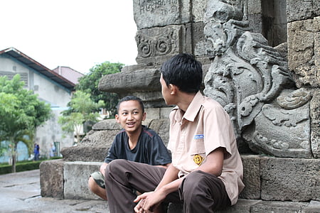 two boys sitting on gray concrete monument thumbnail