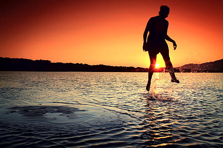 person jumping on beach during golden hour thumbnail