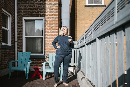 woman standing beside gray fence during daytime thumbnail
