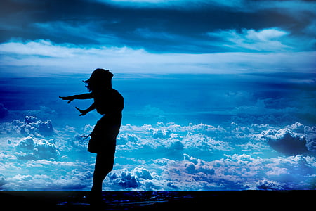 silhouette of standing woman while spreading her arms sideward thumbnail