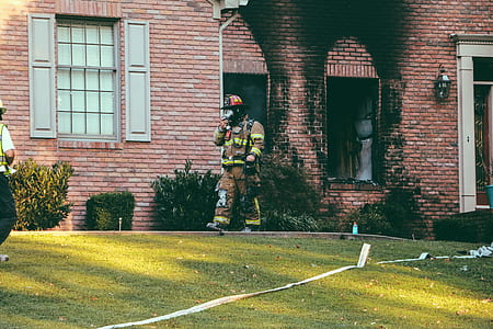 fireman walking in yard outside brown brick house at daytime thumbnail