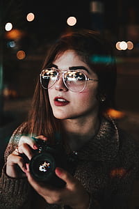 bokeh photography of woman holding DSLR camera thumbnail