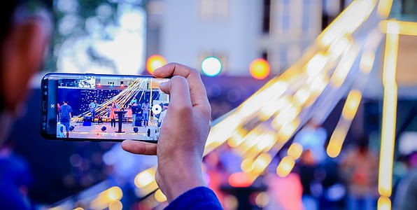 man taking a picture at people at the stage using smartphone thumbnail