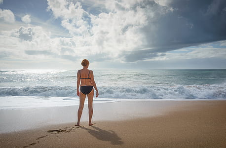 woman in black bikini standing on seashore thumbnail