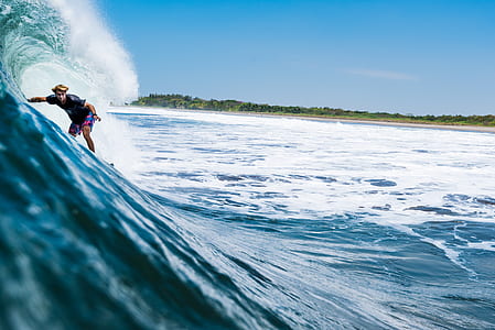 man in blue shirt surfing on blue wave under blue sky closeup photography thumbnail
