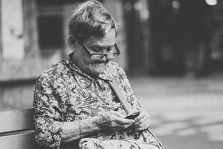 grayscale photography of woman sits on wooden bench thumbnail