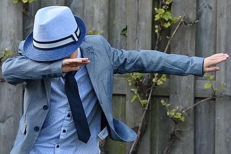 man covering his face using right hand standing near brown wooden fence thumbnail