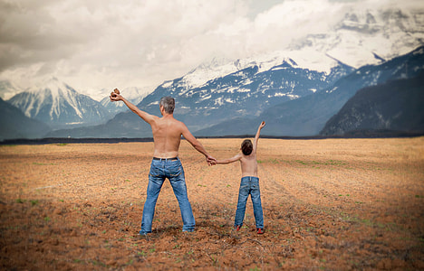 two topless man and child in front of ice-caped mountains thumbnail