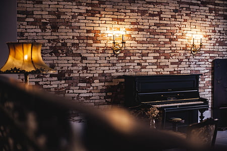 black upright piano next to brick wall thumbnail