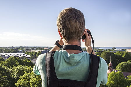standing person taking photo of trees and building at daytime thumbnail