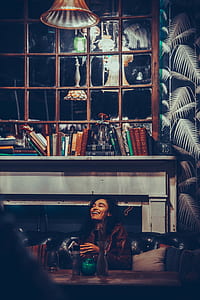 woman laughing while sitting on sofa beside table inside well lighted room thumbnail
