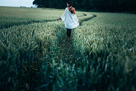 woman walking on pathway between green plants thumbnail