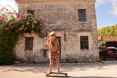 woman riding skateboard in front of gray concrete building during daytime thumbnail