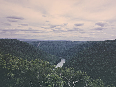 body of water near green mountain under blue sky at daytime thumbnail