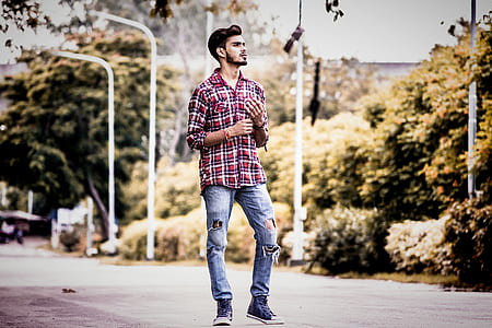 man in plaid sport shirt and distressed jeans standing on road thumbnail