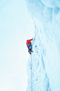 person climbing mountain filled with snow during daytime thumbnail