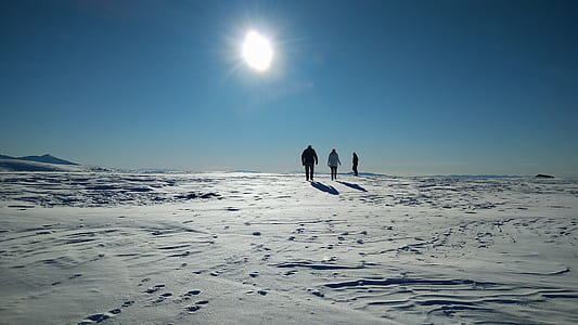 three person walking on snow during daytime thumbnail