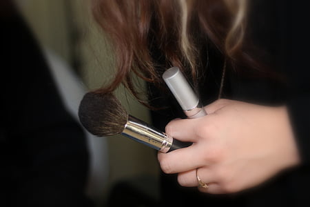 woman holding black and brown makeup brush thumbnail