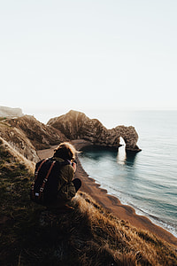 man sitting on brown field near body of water thumbnail