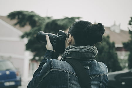 woman in blue denim top taking photo near tree thumbnail
