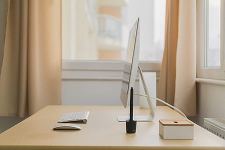 photography of white flat screen monitor and wireless keyboard on brown wooden table thumbnail