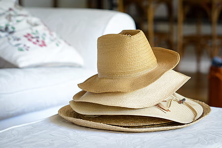 stack of brown sunhats beside white couch thumbnail