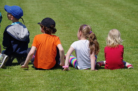 four children sitting on green grass field thumbnail
