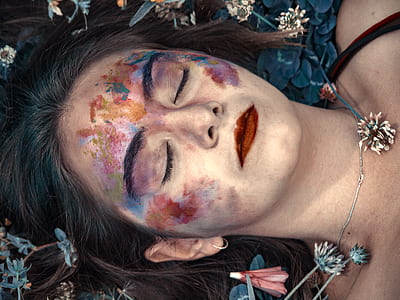 woman lying on flowers closing eyes with makeup stains thumbnail