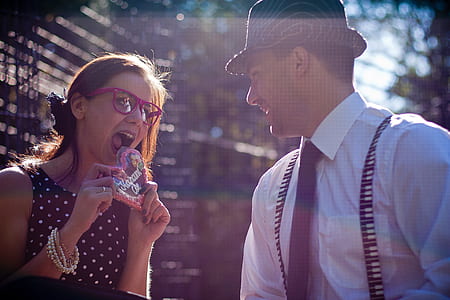 photograph of woman about to heat heart candy in front of a man in hat thumbnail