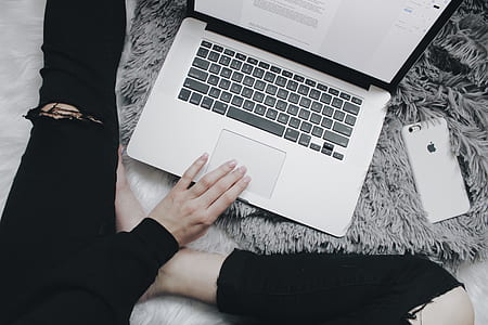 person hand on top of MacBook Pro touch pad sitting on white faux fur rug thumbnail