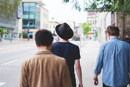 three men walking on road under green tree at daytime thumbnail