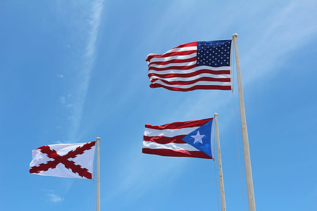 three flags hoisted on poles at daytime thumbnail