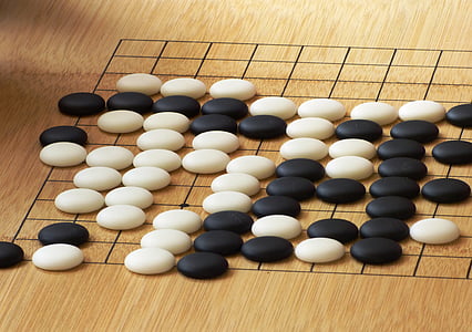 person taking photo of black and white board game pieces thumbnail