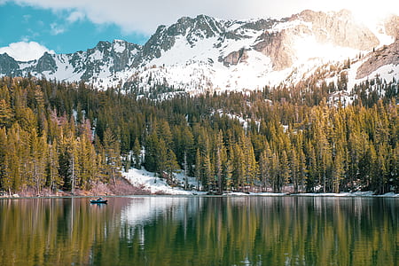 pine trees and mountain covered with snow reflecting on body of water thumbnail