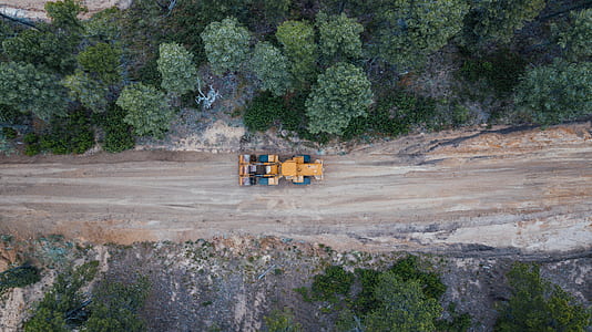 yellow and black heavy equipment beside road and trees thumbnail