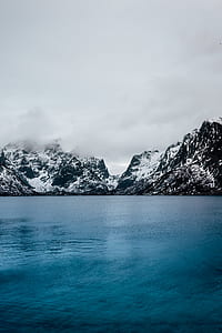 body of water near mountain peaks thumbnail