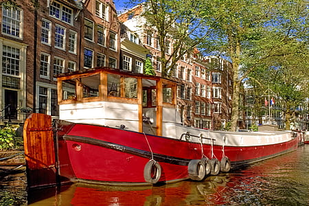 red and white boat on body of water near concrete buildings at daytime thumbnail