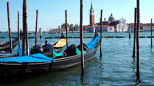 black canoe on body of water far at building under blue sky thumbnail