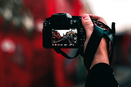 selective focus photography of person holding DSLR focusing on street image thumbnail