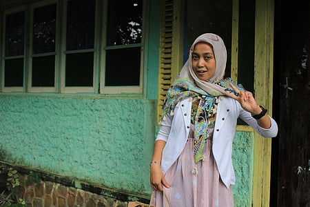 woman doing peace sign near green wall at daytime thumbnail