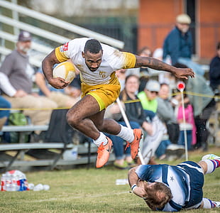 man jumping out of the way of another man who was about to tackle him in a game of rugby thumbnail