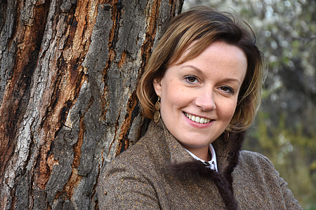 woman wearing brown collared jacket leaning on tree trunk thumbnail