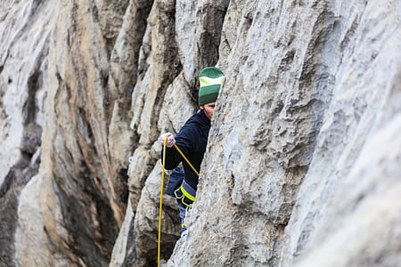 man in black jack climbing beside mountain during daytime thumbnail