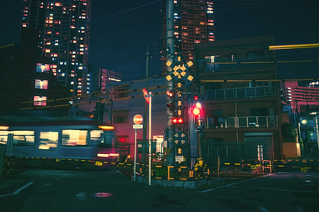 blue train passing through buildings at nighttime thumbnail