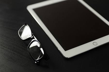 The new 9.7″ iPad Pro tablet with reading glasses on a black desk thumbnail