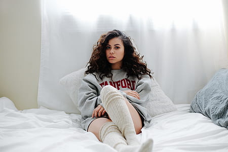 woman in gray sweatshirt sitting on white textile thumbnail