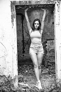 grayscale photograph of woman with her hands up high under door frame thumbnail
