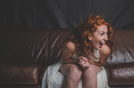 woman wearing white dress sitting on leather couch thumbnail