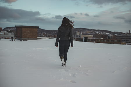 woman walking near snow covered field during daytime thumbnail