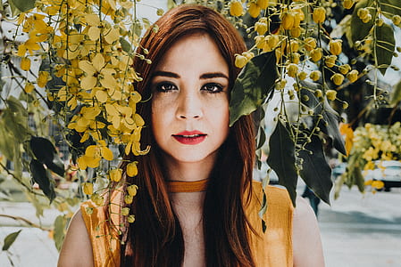 woman standing between yellow flowers during daytime thumbnail
